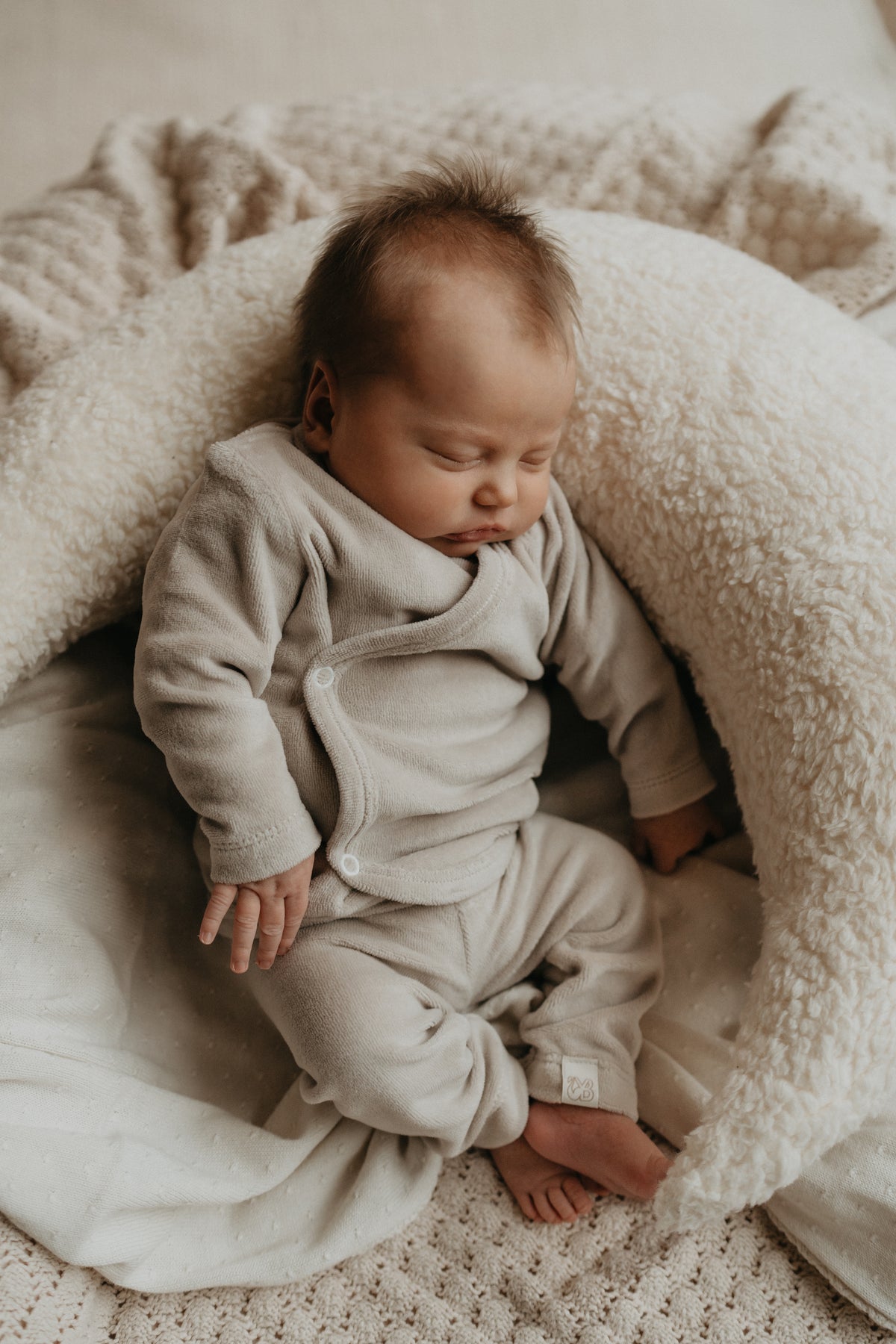 Baby slapend in een maantje in zijn newborn geboortepakje van Yumi Baby