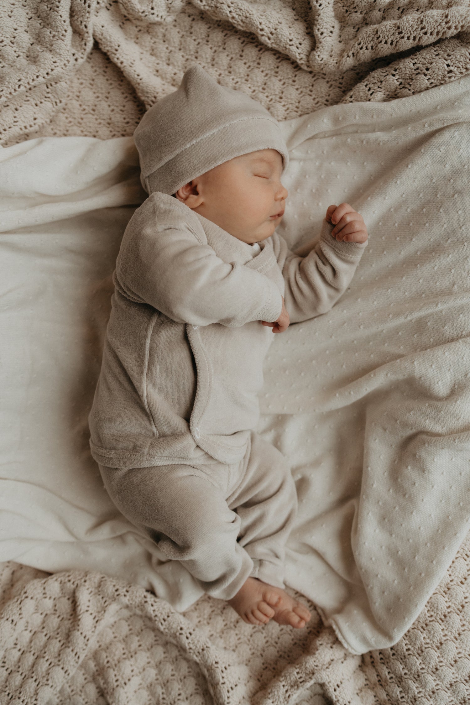 Baby slapend in een beige geboortepakje