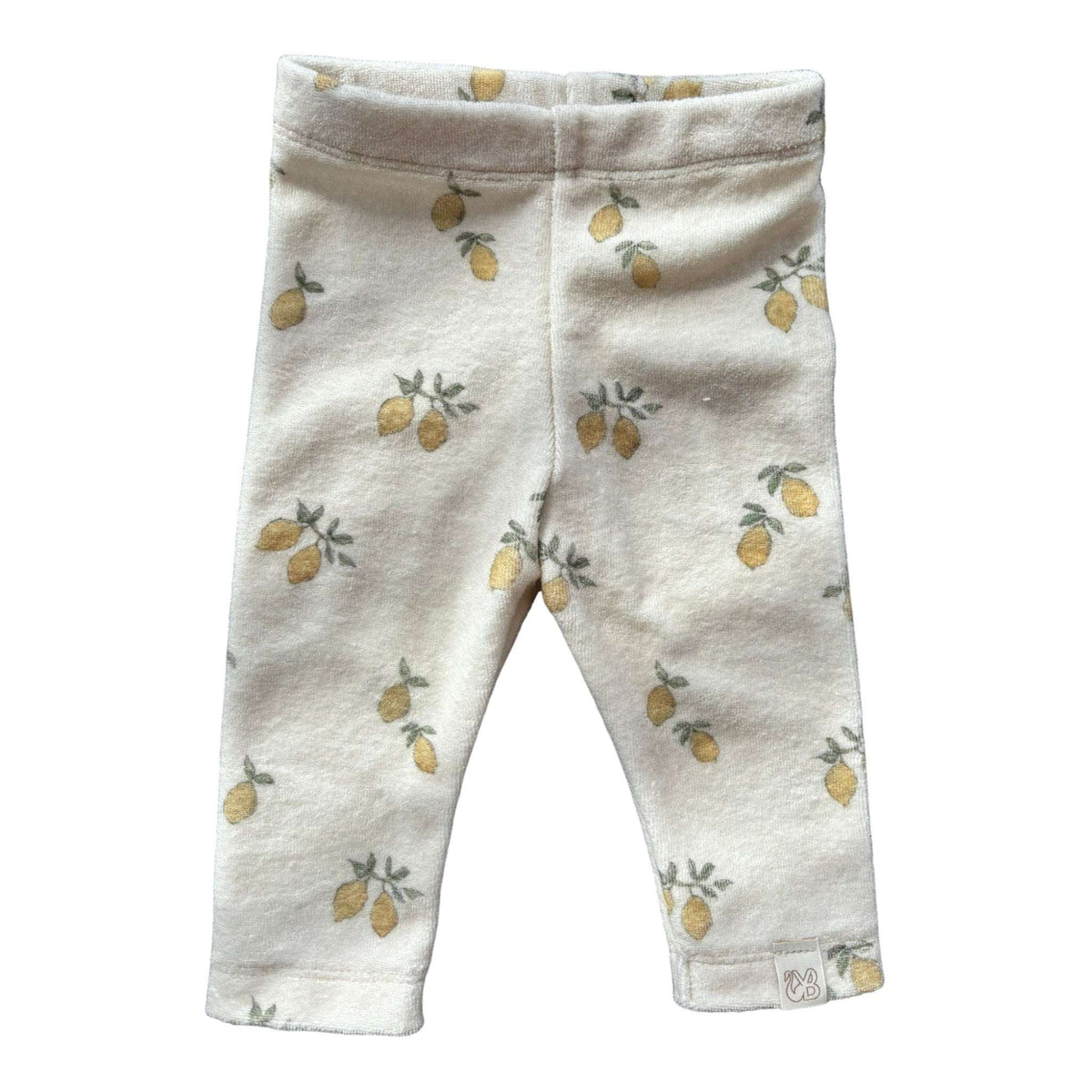 Een babylegging met een witte achtergrond en een patroon van kleine gele citroenen met groene bladeren. Het Broekje Lemon Love van Yumi Baby heeft een elastische taille en is gemaakt van zachte, gezellige badstof katoen, waardoor jouw kleintje comfortabel zit.