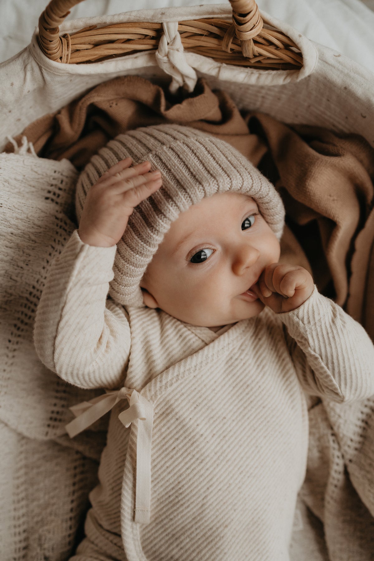 Baby met een duim in de mond en een overslag shirtje van Yumi Baby aan.