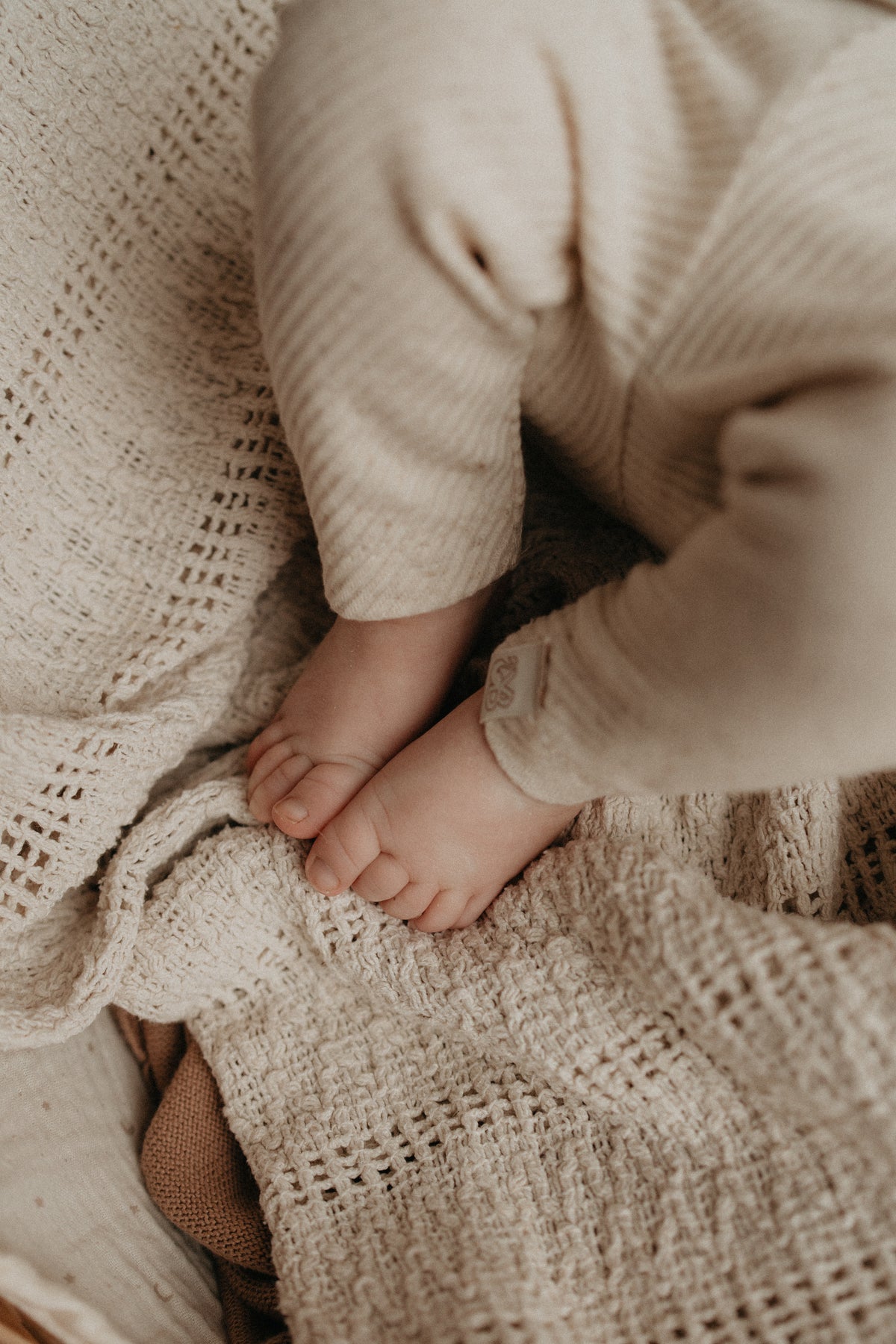 Baby met een Gemeleerd rib baby broekje in creme kleur aan.