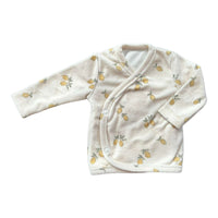 Dit zachte **Yumi Baby** **Oververslagshirt Lemon Love** met lange mouwen is gemaakt van pluizige stof met een citroenpatroon. Het is voornamelijk wit met kleine gele citroenen en groene bladeren en heeft een wikkelsluiting die wordt vastgezet met twee knopen aan de zijkant.