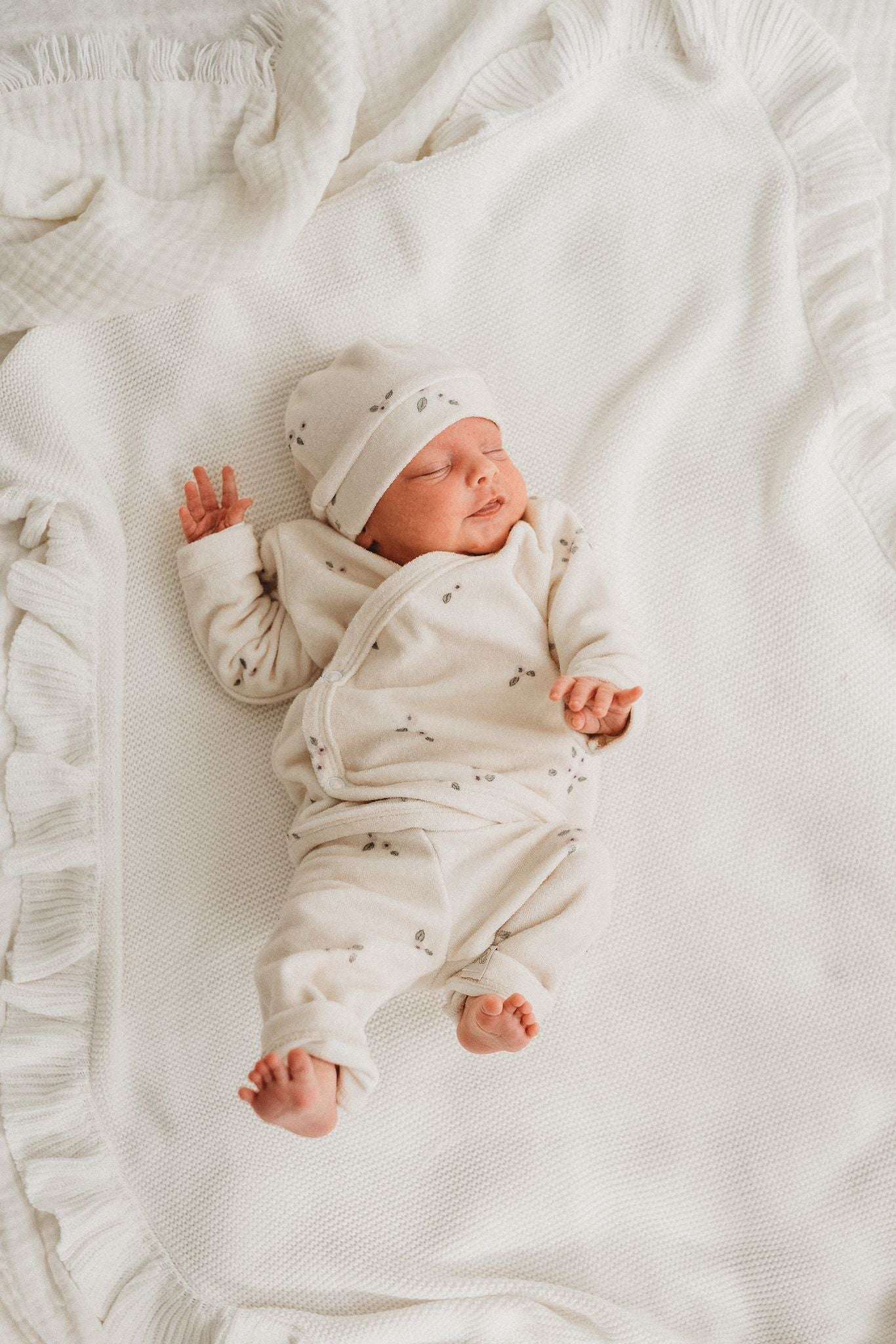 Een crèmekleurige Broekje Blueberry Flower-legging van Yumi Baby, versierd met kleine paarse bloemenprints verspreid over het geheel. De tailleband is elastisch en er zit een stoffen label bij de zoom van het rechterbeen. Gemaakt van zacht badstof katoen, zorgt deze legging voor comfort voor je kleintje.